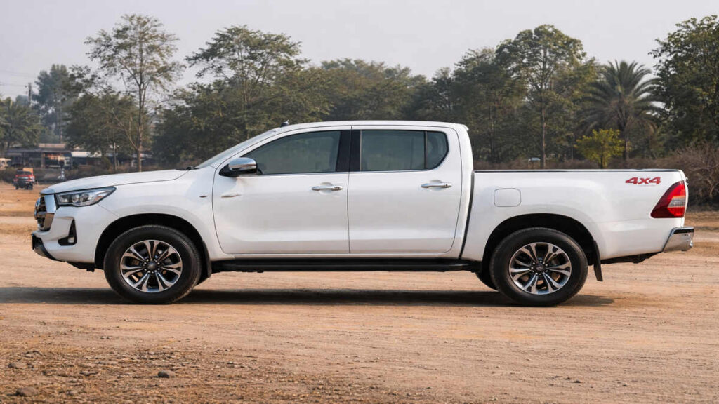 Side profile of Toyota Hilux in white colour parked on open ground, 16:9 realistic pickup look